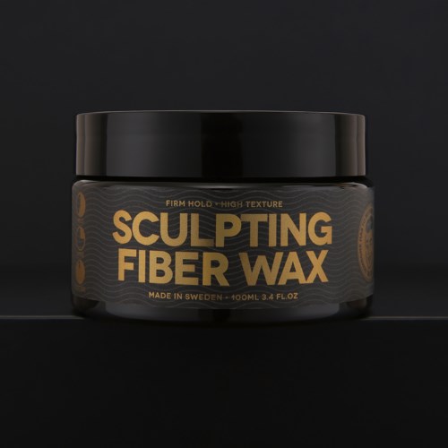 Ein schwarzer Behälter mit goldenem Text sagt 'Sculpting Fiber Wax', hergestellt in Schweden, 100 ml, für Haarstyling.