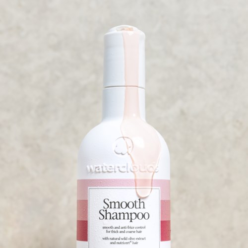 Een witte fles met een roze label en een witte dop, gemerkt 'Smooth Shampoo.'