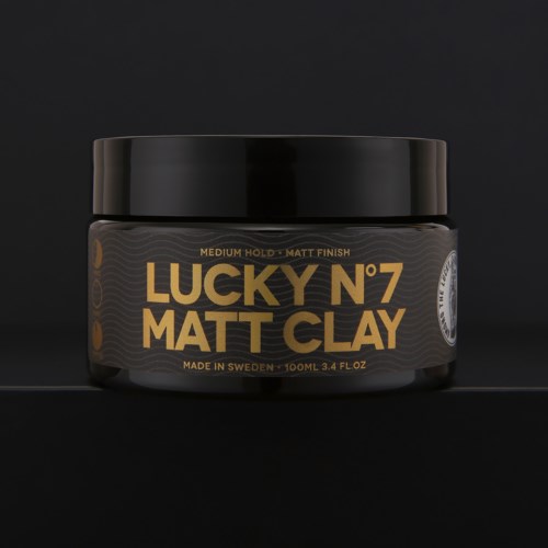 Ein schwarzer Behälter mit goldener und weißer Schrift, die "Lucky N°7 Matt Clay" und Informationen zur Größe und Herkunft zeigt.