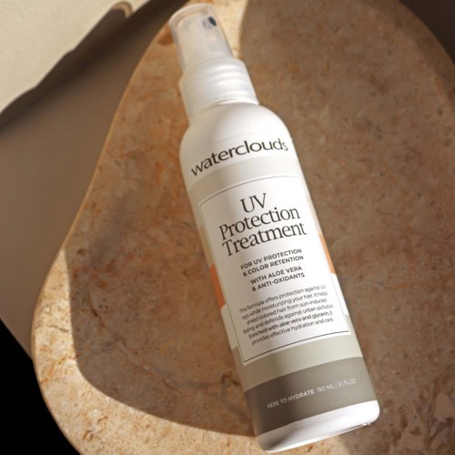 Een witte sprayfles met UV Protection Treatment op een beige oppervlak.