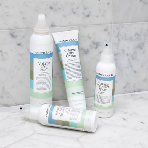 Vier haarverzorgingsproducten van Waterclouds, inclusief droogschuim, zoute crème, volum spray en een tube. Ze liggen op een witte ondergrond.
