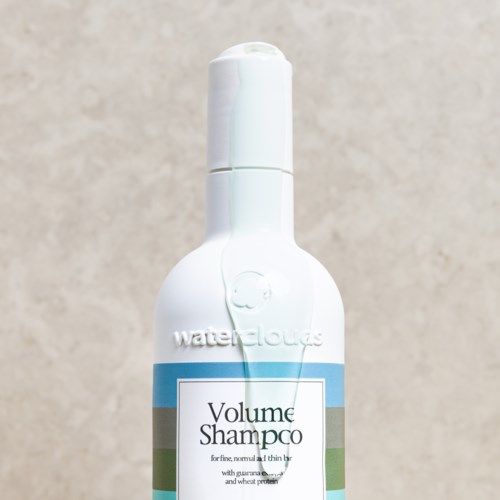Een witte fles Waterclouds Volume Shampoo met blauw en groen label.