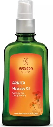 Grüne Flasche mit orangem Etikett, gekennzeichnet Weleda Arnica Massage Oil, verwendet zum Erwärmen und Stärken der Muskeln.