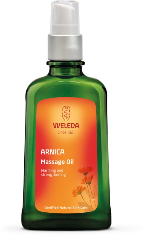 Grüne Flasche mit Weleda Arnica Massageöl, weißer Pumpe, orange Beschriftung und Blumenillustration.