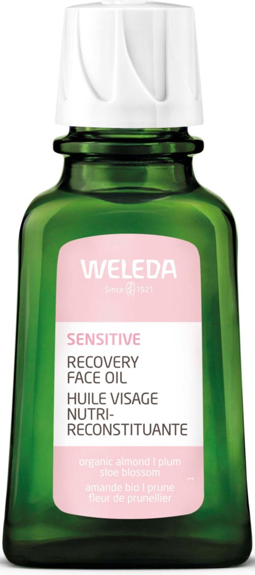 Eine grüne Flasche mit weißem Deckel, beschriftet Weleda Sensitive Recovery Face Oil mit Mandel- und Pflaumenbestandteilen.