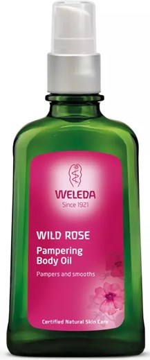 Eine grüne Flasche mit Weleda Wild Rose pflegendes Körperöl mit weißem Pumpverschluss, Etikett mit Produktname und Beschreibung.