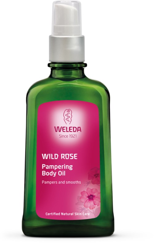 Grüne Flasche mit rosa Etikett, weißer Pumpkopf, enthält Weleda Wild Rose Körperöl für die Hautpflege.