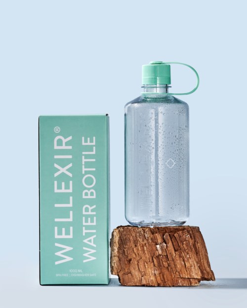 Eine klare Wasserflasche mit grünem Deckel auf einem Holzblock neben einer grünen Schachtel mit der Aufschrift 'WELLEXIR WATER BOTTLE.'