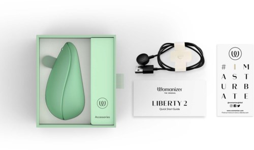 A green device with a charging cable, instruction booklet, and a card with letters and the Womanizer logo.