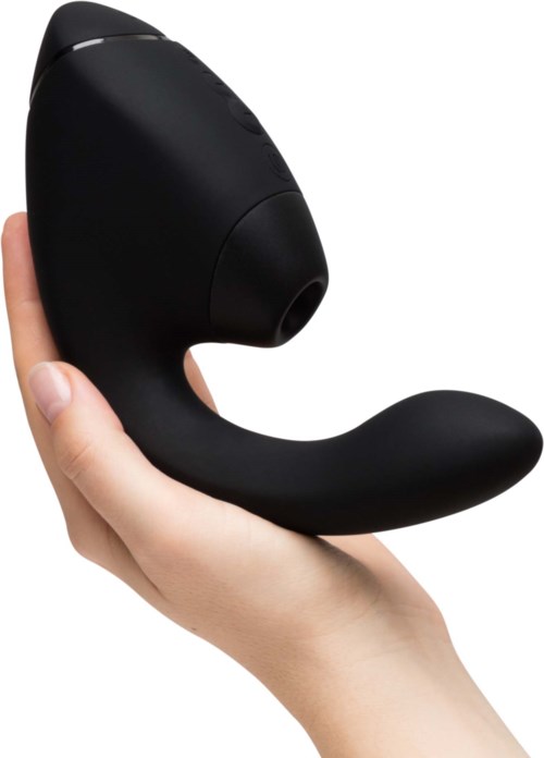 A hand holds a black personal massage device with a curved shape and a rounded end.
