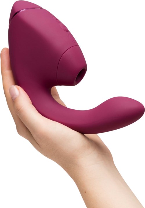 A hand holding a purple, curved personal massager with a round head and a handle.