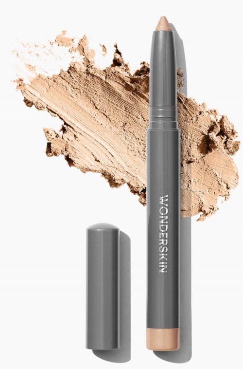 Ein grauer Stift mit Deckel, zerbröckeltes beiges Pulver um ihn, wahrscheinlich ein Make-up-Stick oder Abdeckstift.