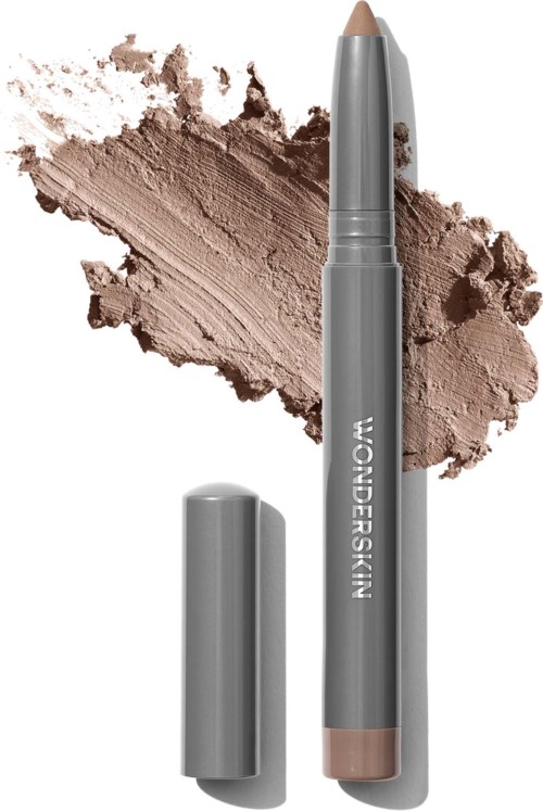 Ein beiger Make-up-Stift mit Deckel, liegt auf einem beige Puderhintergrund, beschriftet 'WONDERSKIN.'