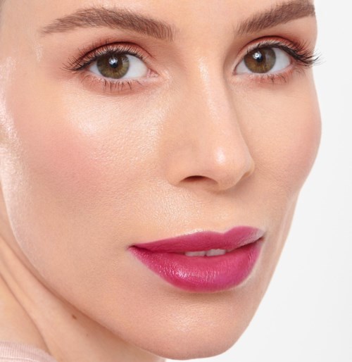 Close-up van een vrouwengezicht met heldere huid, bruine ogen en roze lippen met make-up.