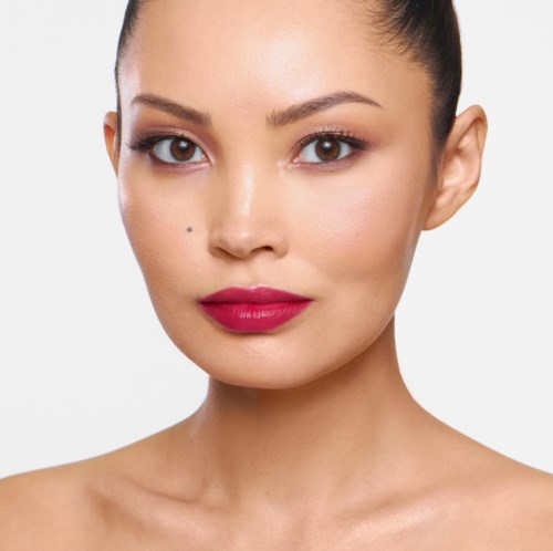 A woman with smooth skin, bold lipstick, and neatly styled hair faces directly, showcasing her facial features clearly.
