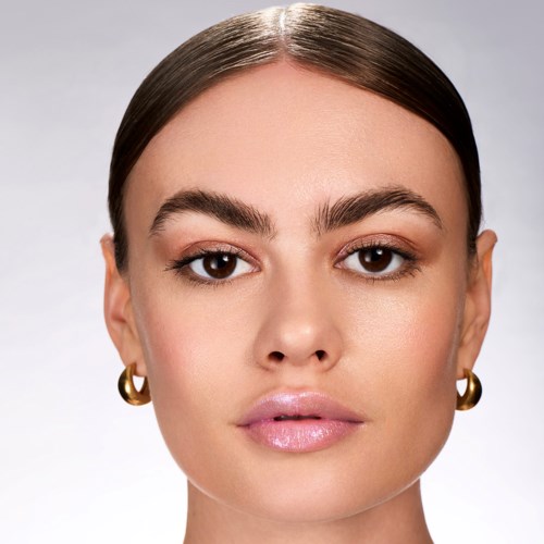 A woman with smooth skin, brown eyes, and long dark hair, wearing gold earrings, looking directly at the camera.