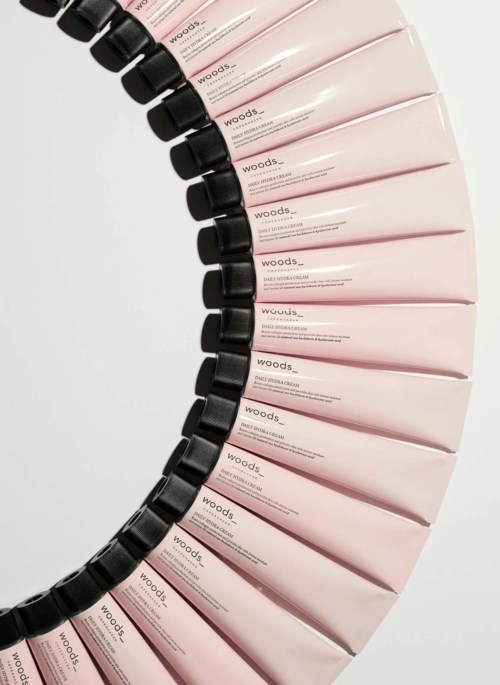 Reihen von rosa Tuben mit schwarzen Deckeln in einer Kurve. Die Tuben haben Text, wahrscheinlich ein Kosmetikprodukt.