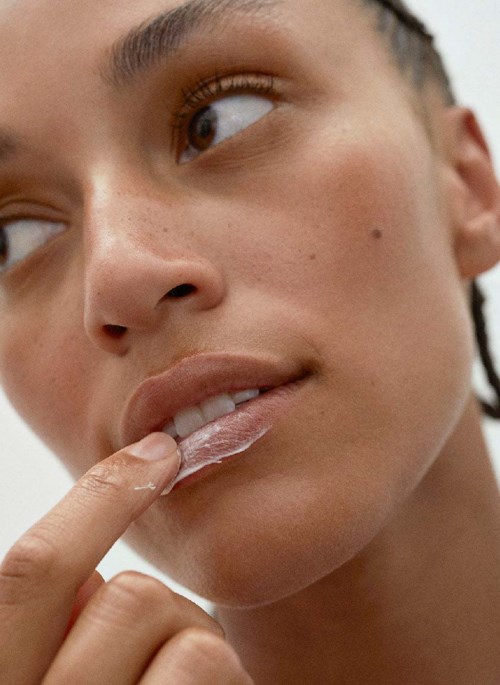 Nahaufnahme einer Person mit braunen Augen, die die Lippen berührt und einen Finger an den Mund legt, schaut zur Seite.
