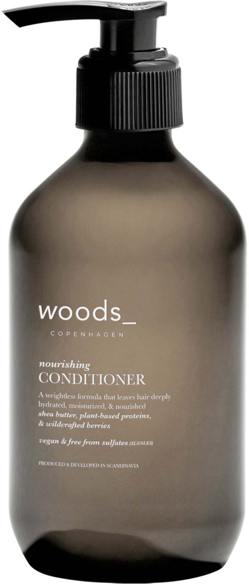 En mørk grå flaske med pumpe merket 'woods' næringsbalsam fra København.