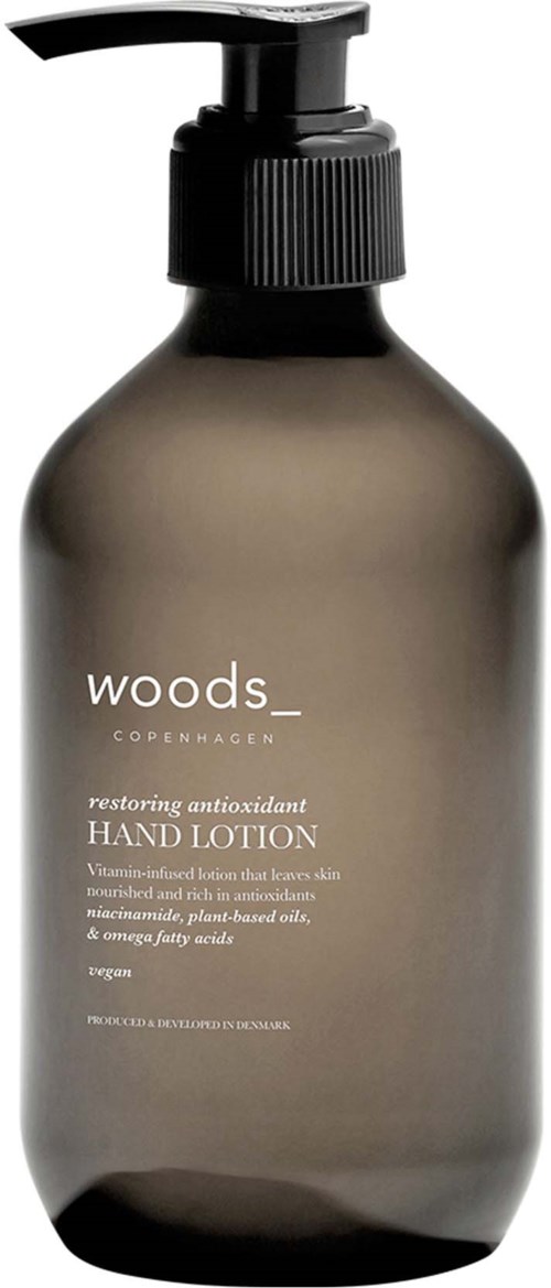 Eine braune Flasche mit schwarzem Pumpkopf enthält Woods Copenhagen Hand Lotion. Sie ist als wiederherstellend und antibakteriell gekennzeichnet.