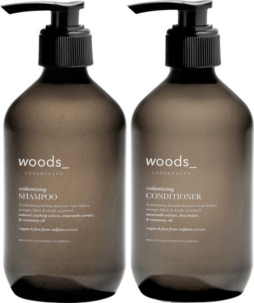 Two brown bottles with black pump dispensers labeled Woods Copenhagen shampoo and conditioner.