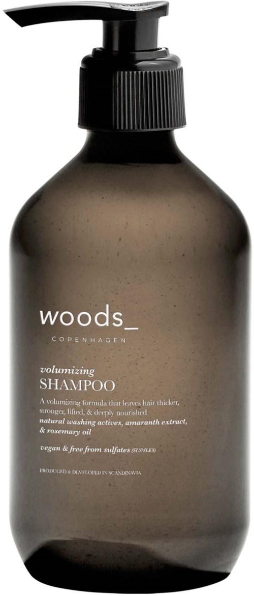 A dark brown shampoo bottle with a pump dispenser, labeled 'woods' and 'volumizing shampoo'.