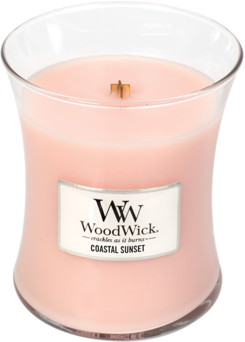 Een roze kaars in een doorzichtige glascontainer met brandende lont, met label 'WoodWick Coastal Sunset'.