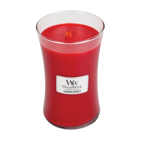 Een rode kaars in een glazen houder met label WoodWick, met kleine vlam en geur van karmozijnrode bessen.