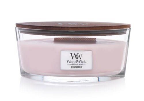 Vaaleanpunainen kynttilä läpinäkyvässä lasipurkissa puupäällä ja merkinnällä 'WoodWick Rosewood.'