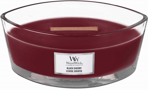 Een donkerroze kaars in een doorzichtige glazen container met een label, gemarkeerd als Black Cherry geur.