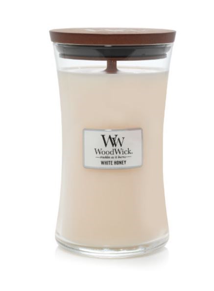 A candle in a glass jar with a wooden lid, labeled 'WoodWick White Honey'.
