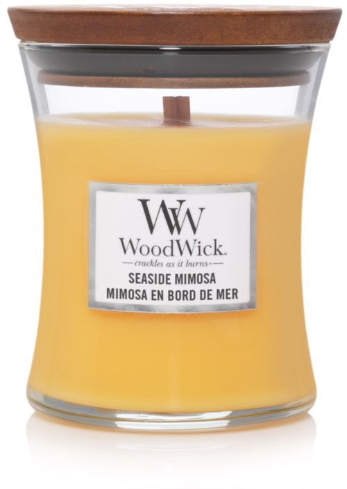 En gul doftljus i glasbehållare med trälock och en etikett som säger WoodWick Seaside Mimosa.