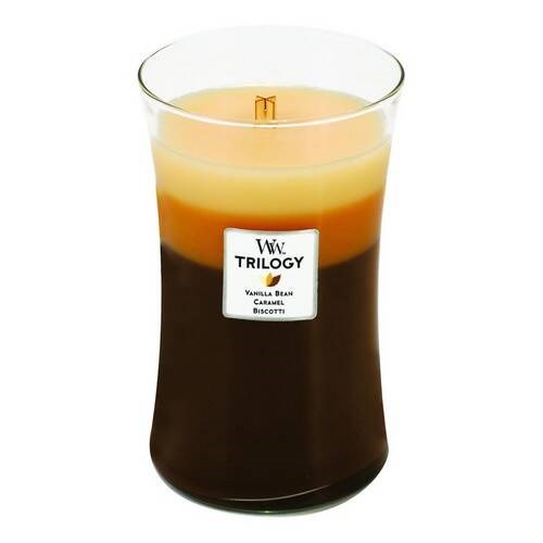 Et stort lys i et glasskrus merket 'Trilogy Vanilla Bean Caramel Biscotti.' Lyset har tre lag med forskjellige farger.