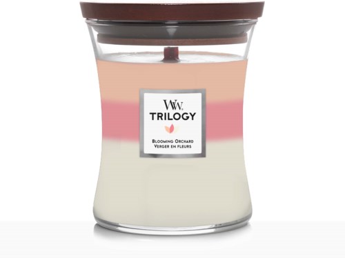 Et duftlys med tre fargede lag og lokk merket 'Trilogy' og 'Blooming Orchard'.