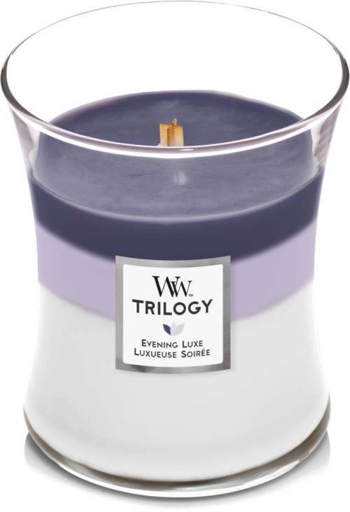 Et lys i glass med lilla og hvit farge og etikett som sier "Trilogy" og "Evening Luxe."