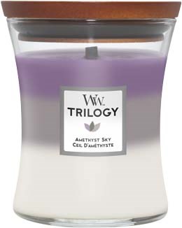 Een lavendelkleurige en witte geurkaars in een doorzichtige pot met houten deksel, label "Trilogy Amethyst Sky."