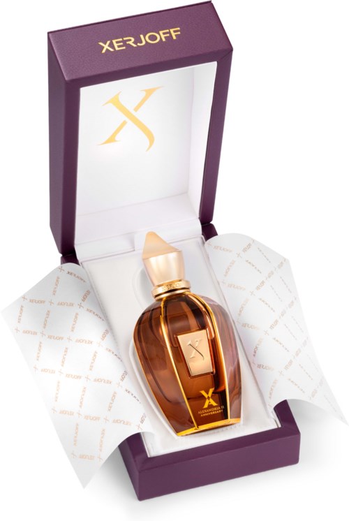 Butelka perfum w fioletowym pudełku z złotym napisem, wyłożona białym papierem, z złotym logo 'X' w środku.