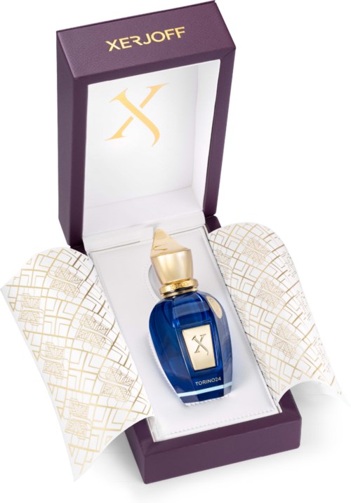 Een blauw parfumflesje met een gouden dop in een paarse doos, met wit papier en de merknaam 'XERJOFF'.