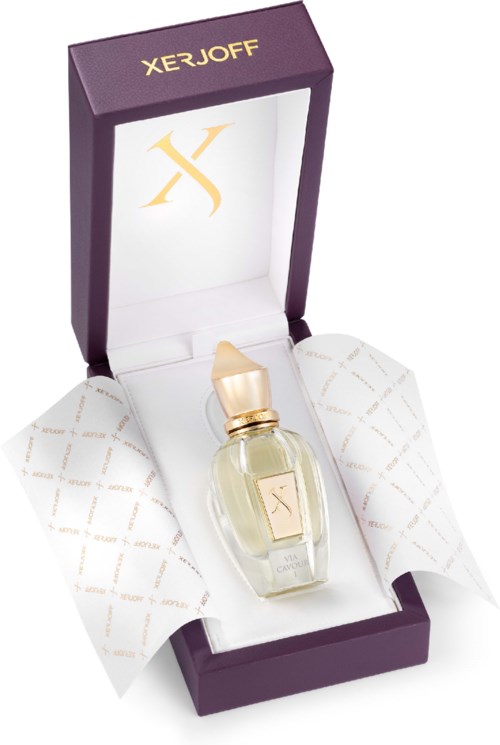 A small perfume bottle with a cream-colored cap in a purple box. The box has gold and white branding inside and outside.