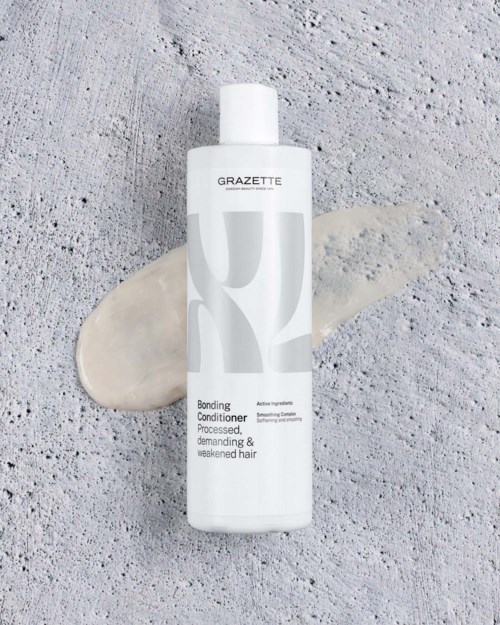 Grazette bonding conditioner voor behandeld, veeleisend en verzwakt haar, met een witte en grijze fles op een gestructureerde ondergrond.