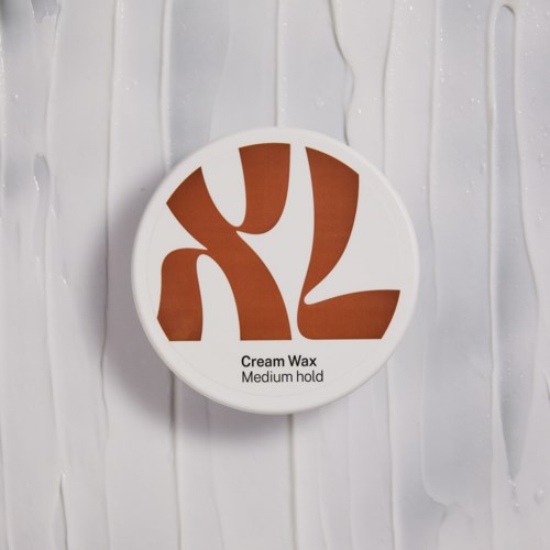 Ein runder Behälter mit weißem Deckel und braunem Design, beschriftet 'Cream Wax, Medium hold'.