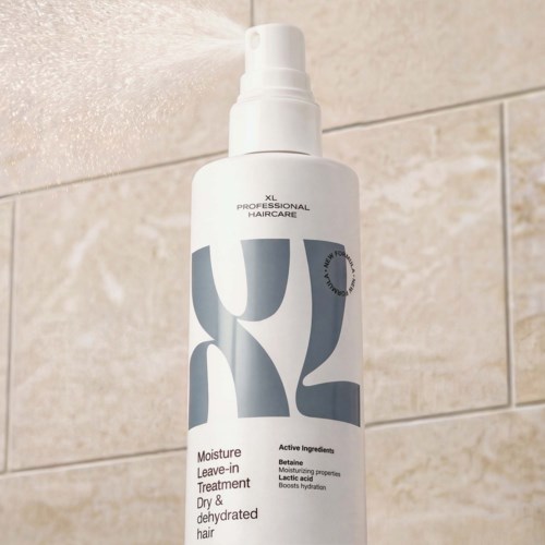 White haircare spray bottle with XL Professional Haircare logo and text, placed against beige tile background.