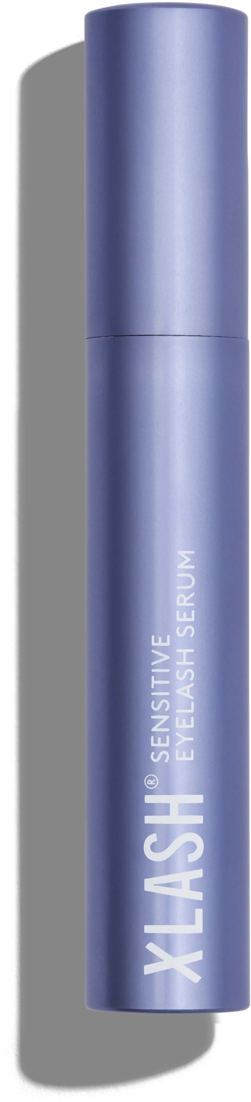 Een blauwe cilindervormige fles met Xlash Sensitive wimperserum op een zwarte achtergrond.