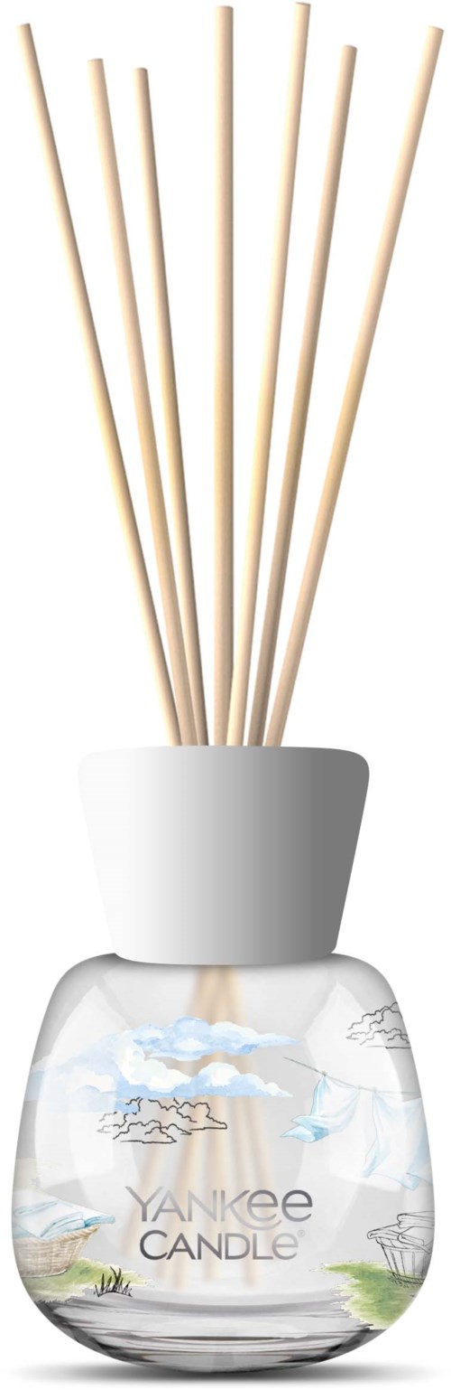 Een Yankee Candle-verdamper met meerdere houten stokjes in een glazen container met een landschapontwerp.