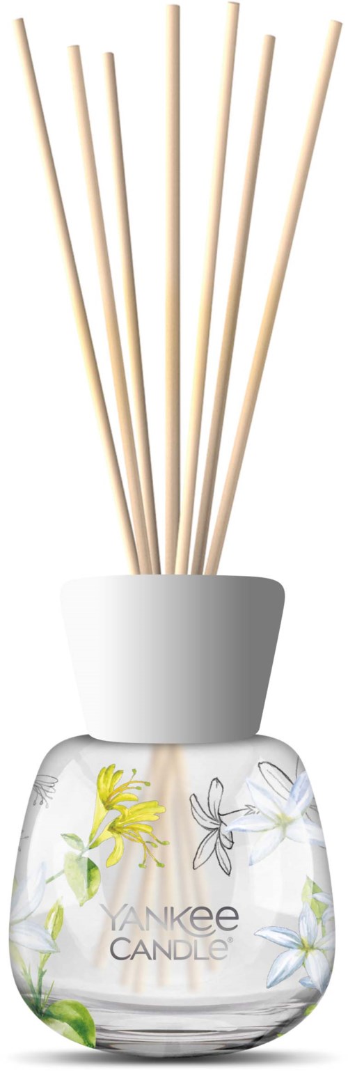Ett tydligt glasrör med blommönster innehåller doftdiffusorer med träpinnar. Jagaren är märkt "Yankee Candle."