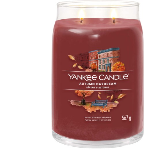 Een grote roze kaars in een glazen pot met twee brandende ganzes en herfstthema op het label.