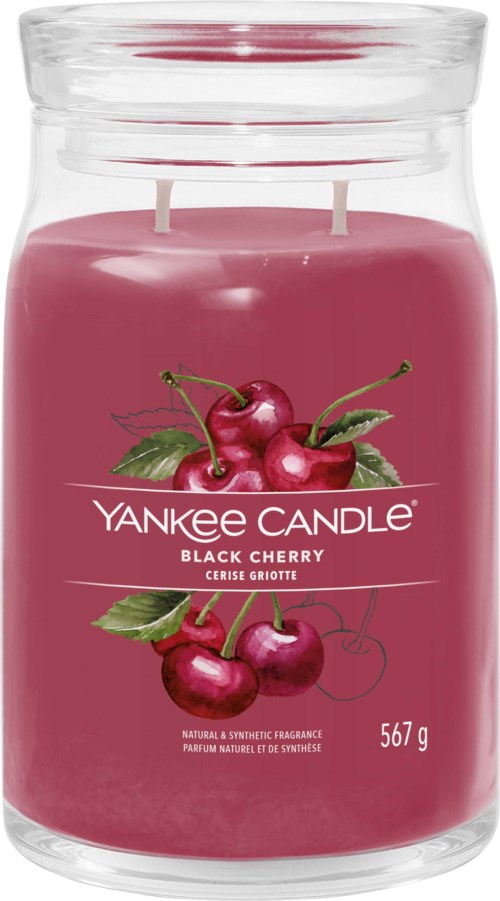 A pink candle in a clear jar with cherry illustrations and the brand name Yankee Candle written on the label.
