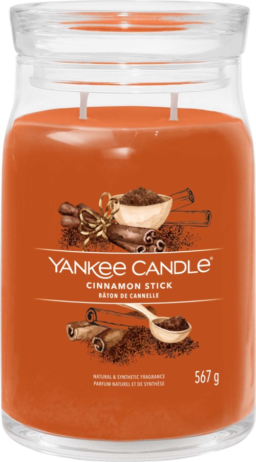Grote oranje geurkaars in een glazen pot met twee lonten, label Yankee Candle Cinnamon Stick.