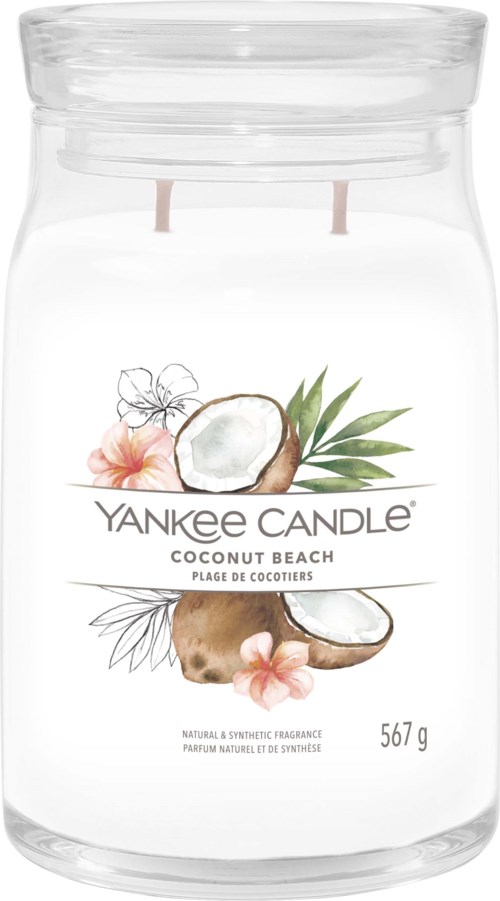 Ett klart glasskrus innehåller ett vitt ljus med en etikett som visar kokos och blommor, med temat Yankee Candle Coconut Beach.