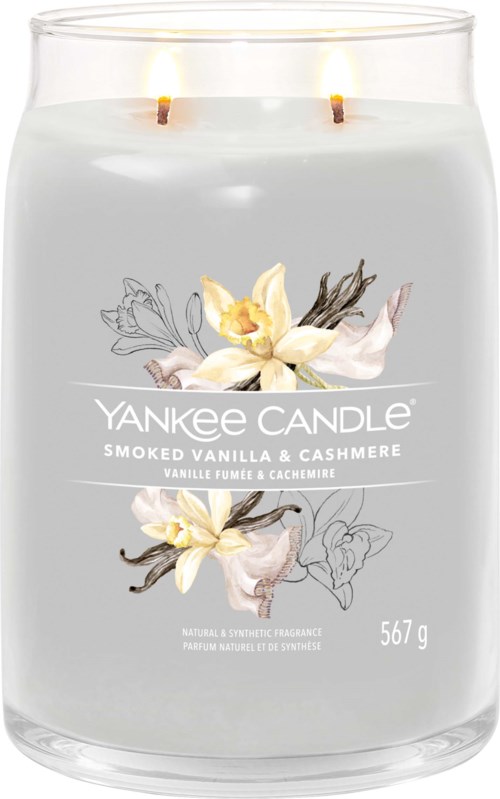 Een witte kaars in een glazen pot met twee brandende lonten, gemarkeerd 'Yankee Candle' met vanille en cashmere geur, weegt 567 g.
